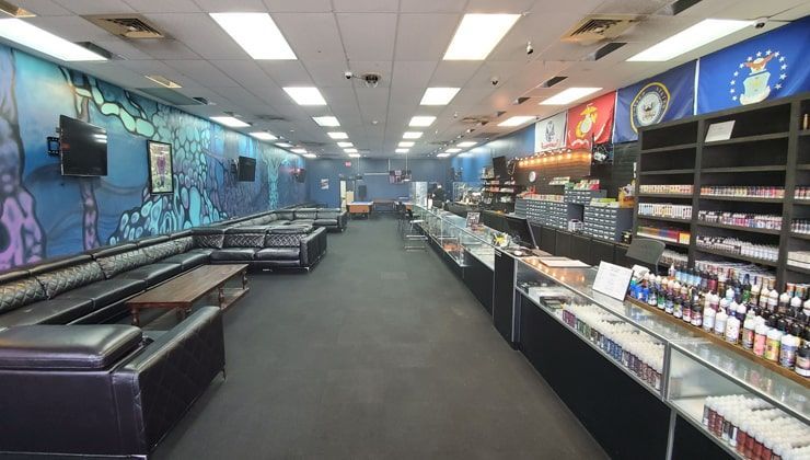Long sales floor at Cloud 9 Vapes on Airport Blvd in Mobile, AL, with leather couches, a mural and glass display counters