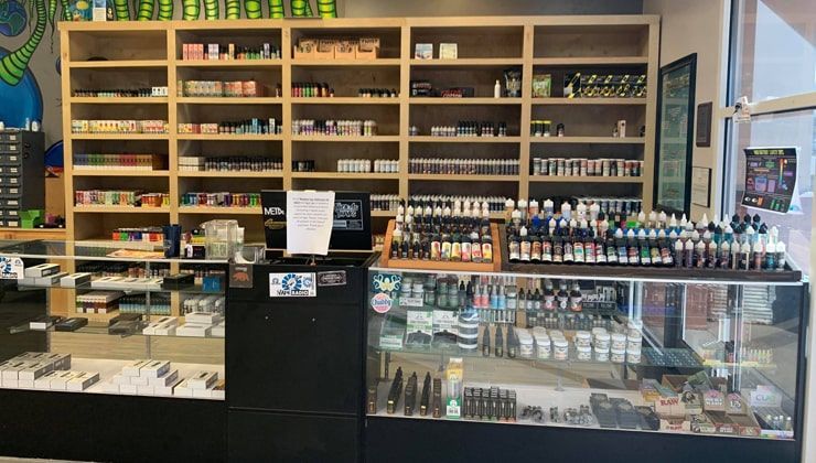 Wood shelves of e-liquid and devices above the glass counter at Cloud 9 Vapes in Daphne, AL