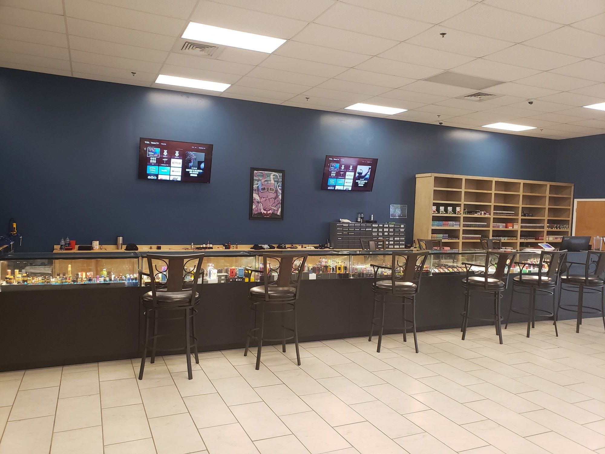 Long glass counter with bar stools and TVs at Cloud 9 Vapes in D'Iberville, MS