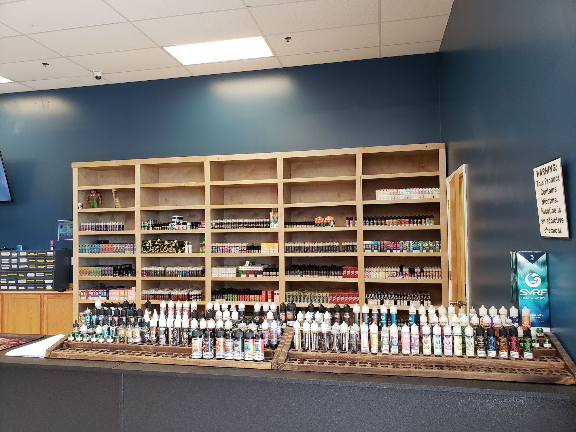 Wood shelves of e-liquid behind a counter display of bottles at Cloud 9 Vapes in D'Iberville, MS
