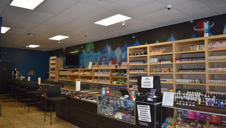 Bar seating along the glass display counter at Cloud 9 Vapes Hillcrest in Mobile, AL