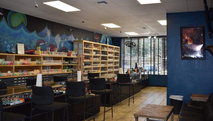 Wide view of Cloud 9 Vapes Hillcrest in Mobile, AL, with bar stools, a mural and e-liquid shelves