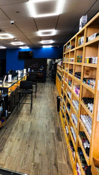 Floor-to-ceiling wood shelving stocked with e-liquid at Cloud 9 Vapes in Saraland, AL